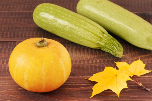 Pumpkin and zucchini on wooden table with autumn leaves. Food and drink, holidays, halloween concept