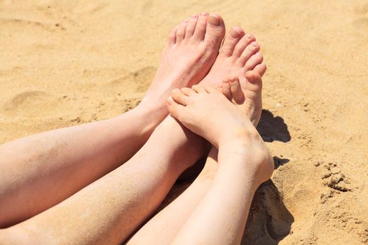 Feet of mother and her child in the sand