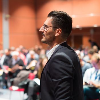 Speaker giving a talk on corporate Business Conference. Audience at the conference hall. Business and Entrepreneurship event.