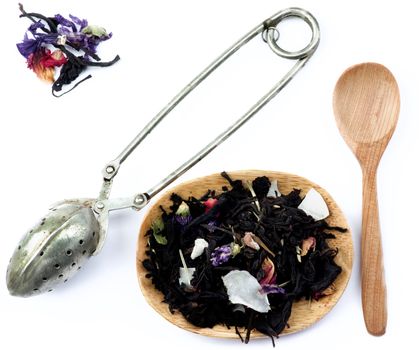 Tea Leafs Concept with Vintage Brewing Spoon, Heap of Tea with Fruits and Flowers Leafs in Wooden Plate and Wooden Spoon closeup on White background 