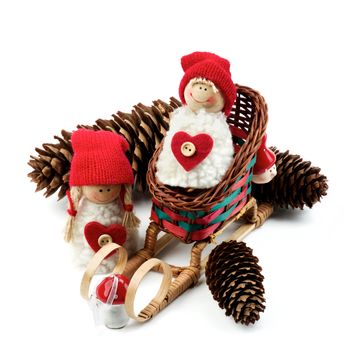 Christmas Decoration Concept with Handmade Dolls in Knit Hats, Fir Cones in Sleigh closeup on White background