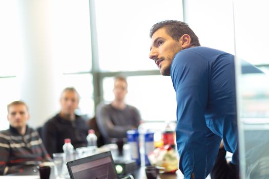 Business man making a presentation at office. Business executive delivering a presentation to his colleagues during meeting or in-house business training, explaining business plans to his employees.