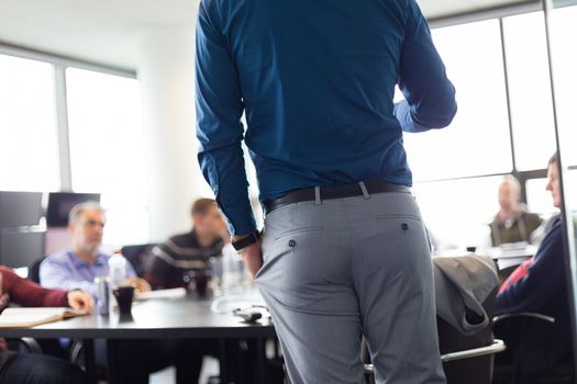 Business man making a presentation at office. Business executive delivering a presentation to his colleagues during meeting or in-house business training. Rear view. Business and entrepreneurship.