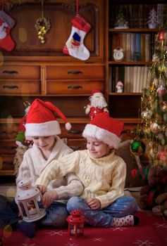 Two kids playing under Christmas tree