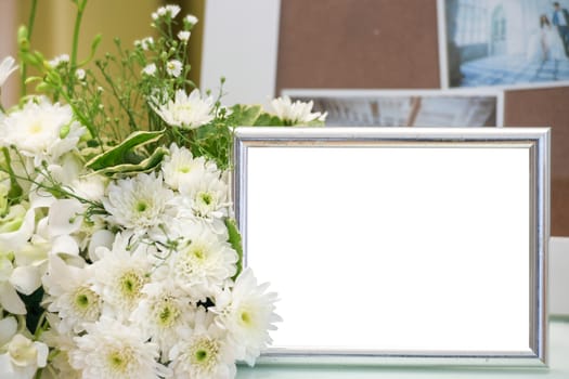 Blank vintage photo frame and flower on wooden background.