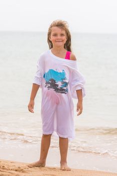 Cheerful girl basking on the beach wearing a large T-shirt parent