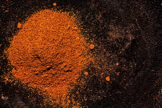 Pile of ground paprika on a textured dark background. Handful of fragrant spicy seasonings - top view with copyspace.