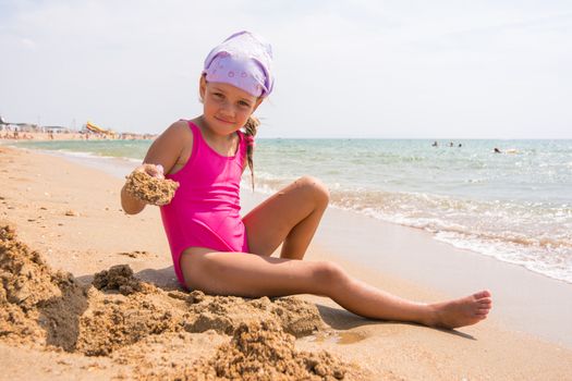 Girl digs a hole in the sand on the seashore