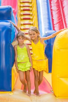 Two children stand at the entrance of a large inflatable trampoline