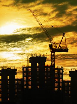 silhouette of crane and building construction and sun set sky with copy space use for construction industry business theme