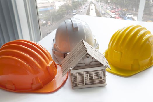 model of wood house made from wood stick on architect working table with varities color of safety helmet 