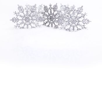 Decorative silver snowflakes on snow, white copy space