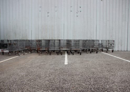 Industrial Iron Trolleys at Grey Empty Parking  Lot with White Stripes