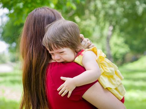 Mother holding her crying one-year old baby girl with tears close up