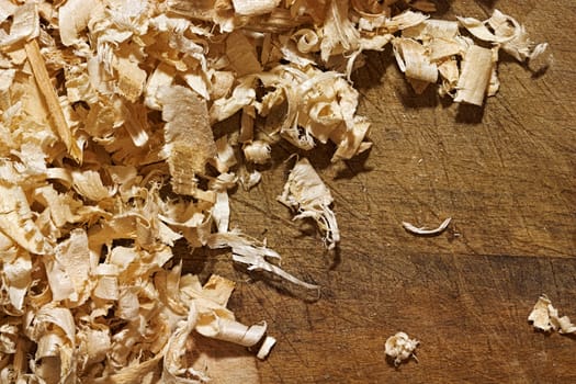 Thin, soft, twisted wood shavings on the rough wooden background. Backdrop with copyspace for the woodworking, carpentry, DIY themes design.