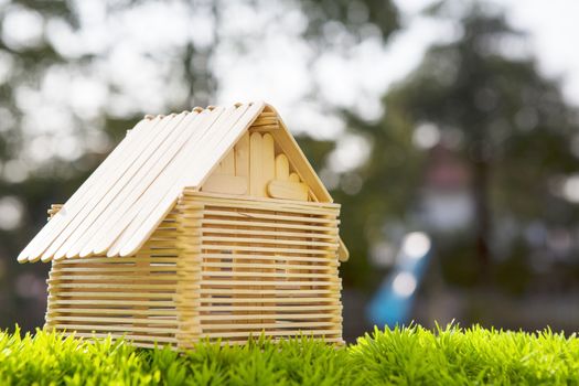 house model make from wood stick on artificial grass field with blurry background use for home nad housing abstract model