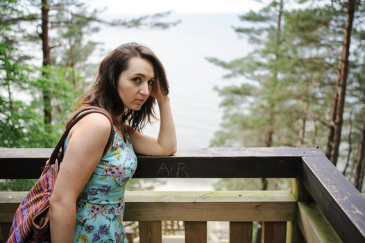 Brunette girl sitting on the wooden stairs in park and smiling