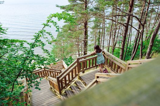 Brunette girl sitting on the wooden stairs in park and smiling
