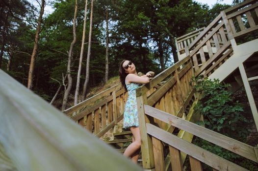 Brunette girl sitting on the wooden stairs in park and smiling