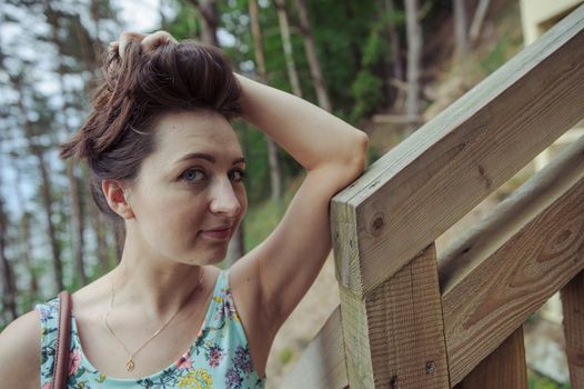 Brunette girl sitting on the wooden stairs in park and smiling