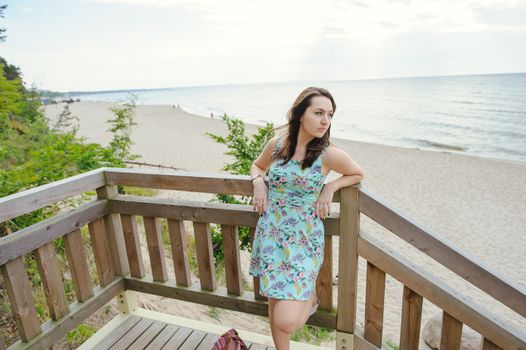 Brunette girl sitting on the wooden stairs in park and smiling