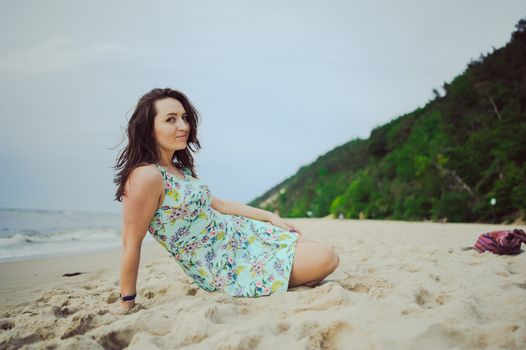 Young attractive brunette woman on a beach wearing dress