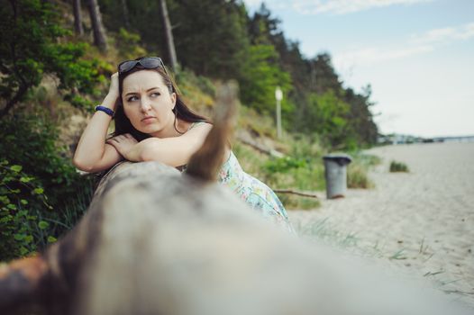 Young attractive brunette woman on a beach wearing dress