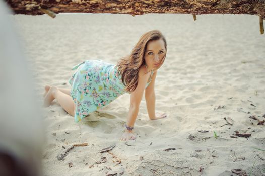 Young attractive brunette woman on a beach wearing dress