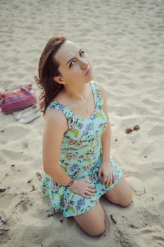Young attractive brunette woman on a beach wearing dress