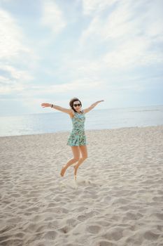 Young attractive brunette woman on a beach wearing dress