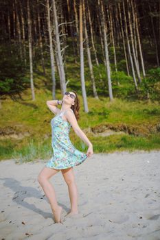 Young attractive brunette woman on a beach wearing dress
