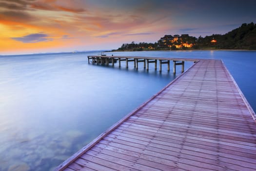 wood bridge piers with nobody and smoothy sea water against beautiful sun rising sky