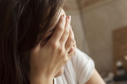 Brunette girl with headache holding hand on her head.