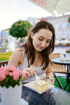 girl eating piece of fondant cake on table, outdoor restaurant
