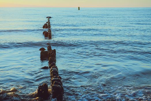 Breakwaters in the Baltic sea over the sunset in summer