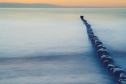Breakwaters in the Baltic sea over the sunset in summer