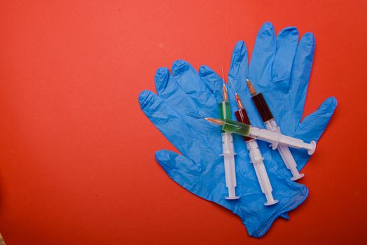 Hand in glove with syringe on red background. Injections.