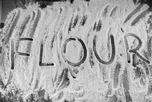 Word flour written in flour on table.