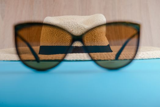 Straw hat and sunglasses on blue background. beach equipment.