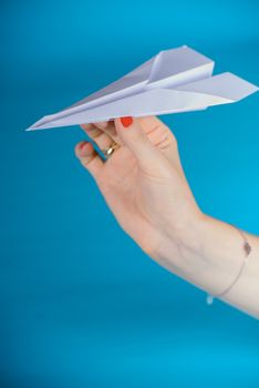 Paper plane in female hand on a blue background