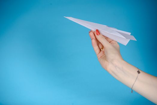 Paper plane in female hand on a blue background
