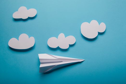 Paper plane in female hand on a blue background with clouds