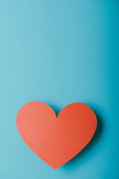 Red paper Valentines Day heart against a blue background