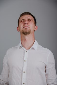 young man with a strong pain against gray background