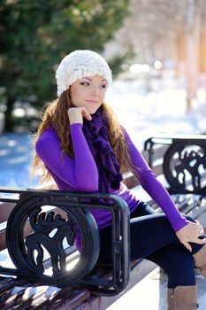 Beautiful girl sitting on a bench in winter