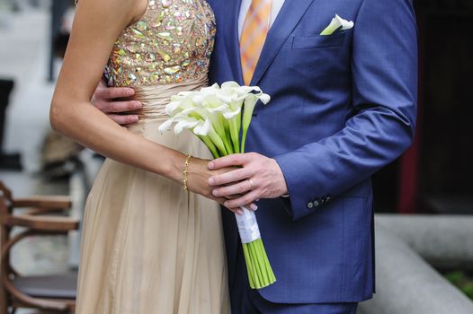 bride and groom holding a wedding bouquet of callas 