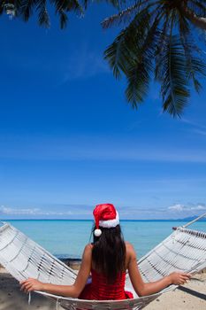 Woman in hammock on tropical beach celebrating Christmas