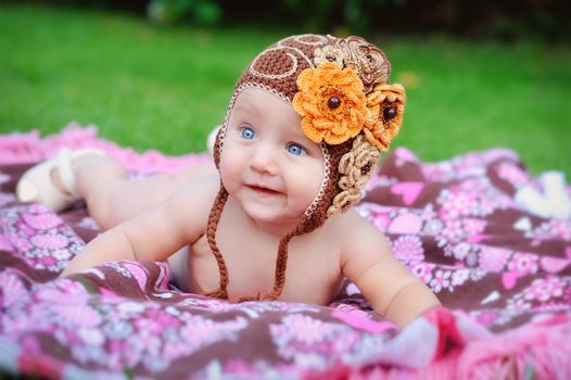 Charming child. Little girl with hat lying on her stomach