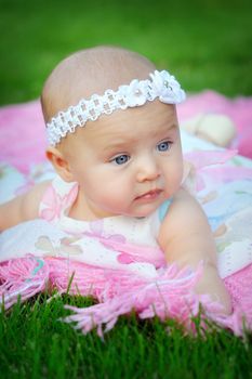 Portrait of little cute baby girl lying in the park and a bandage on his head