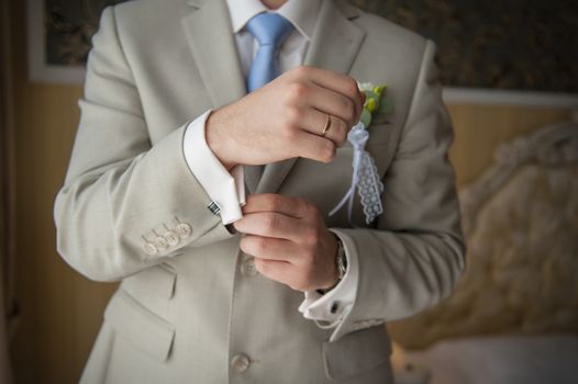 Hands of wedding groom getting ready in suit. 